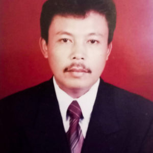 A picture of a Ibu Dwi Restu's husband, dressed in a suit and tie on a red background