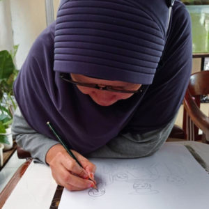 Ibu Suyanah is drawing out their final design with a pencil